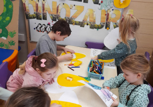Dzieci wykonują prace plastyczną przy stolikach pt. "Jajo dinozaura"