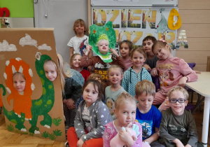Grupa dzieci pozuje do zdjęcia na tle dekoracji z okazji Dnia Dinozaura