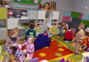 Dzieci układają w sali wieże z plastikowych kubeczków.