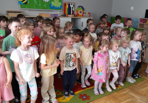 Dzieci stoją na dywanie, żywo reagując na polecenia aktorów