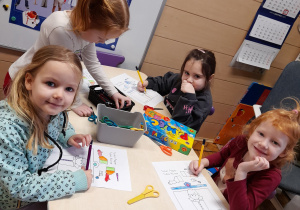 Przy stoliku znajduja się cztery dziewczynki, które wykonuja prace plastyczną związana z zawodami.