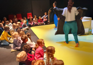 Spektakl teatralny, aktorzy z wielkimi poduchami z dłoniach prezentują swoją sztukę.