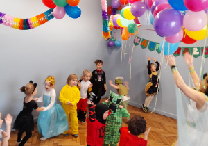 Dzieci tańczą na sali udekorowanej kolorowymi balonami, serpentynami.