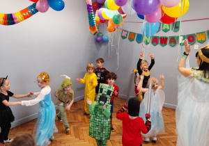 Dzieci tańczą na sali udekorowanej kolorowymi balonami, serpentynami.